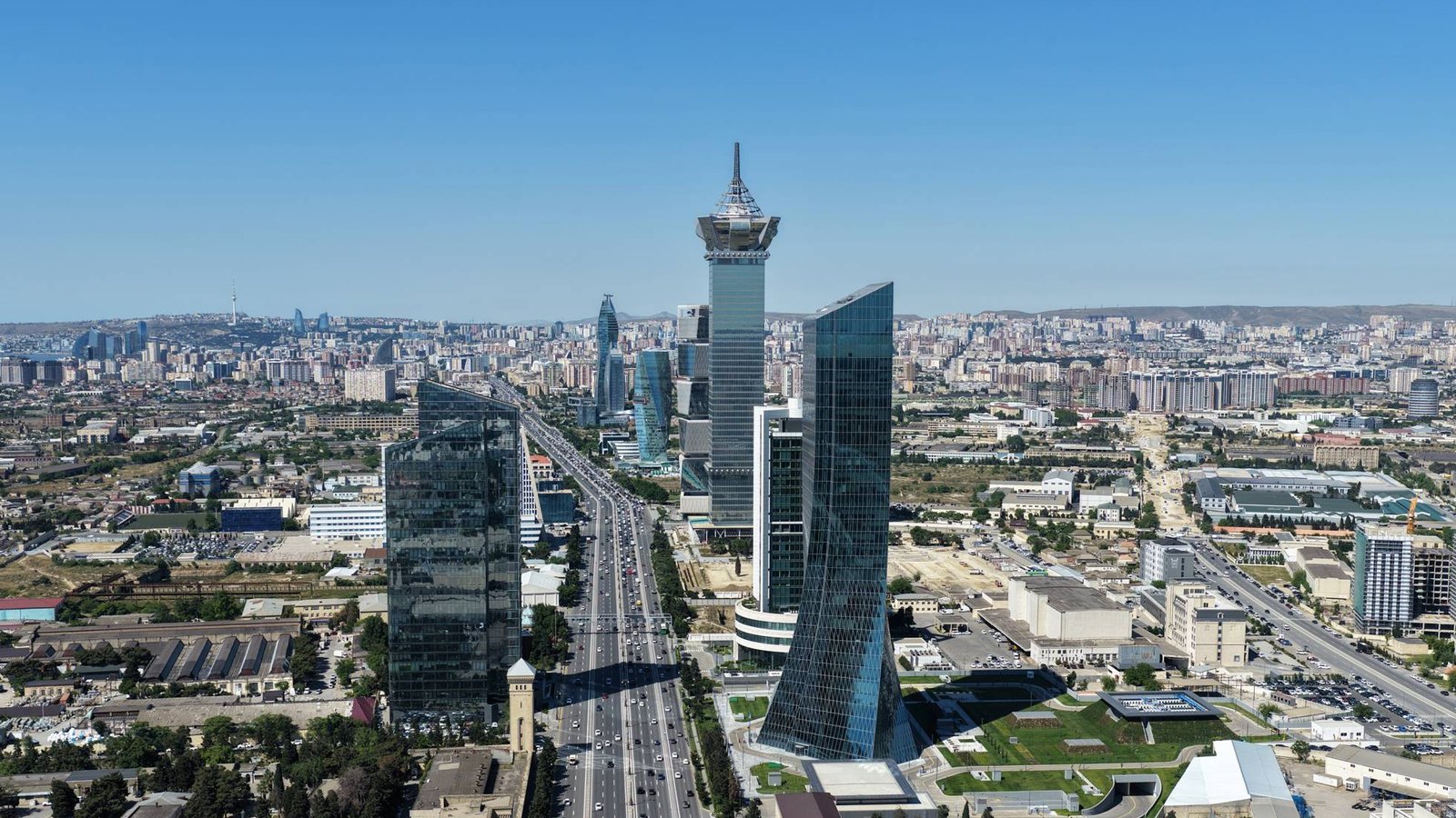 Aerial view of glass skyscrapers along a wide multi-lane avenue running through a sprawling city
