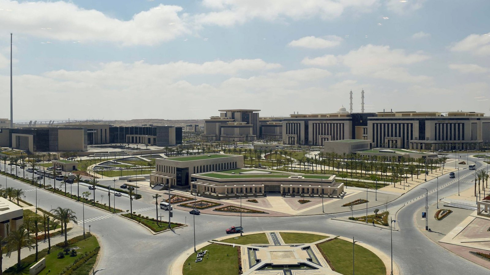 Wide landscaped roads with palm trees and roundabouts between large pale government buildings