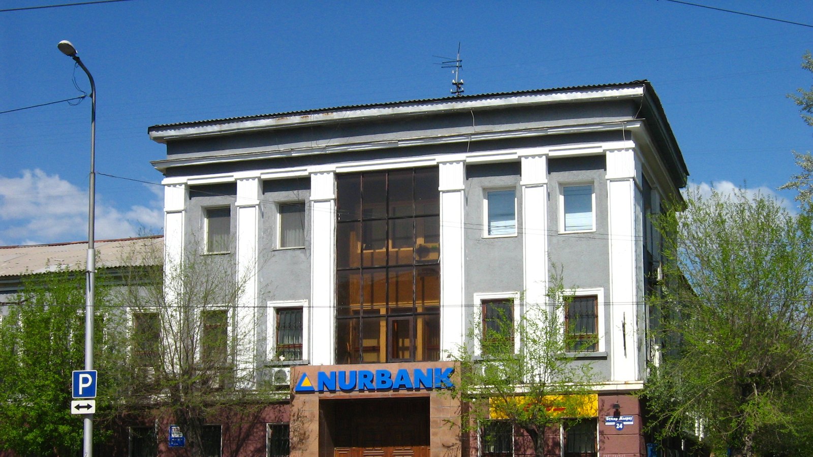 A three-storey grey building with a Nurbank sign over the entrance