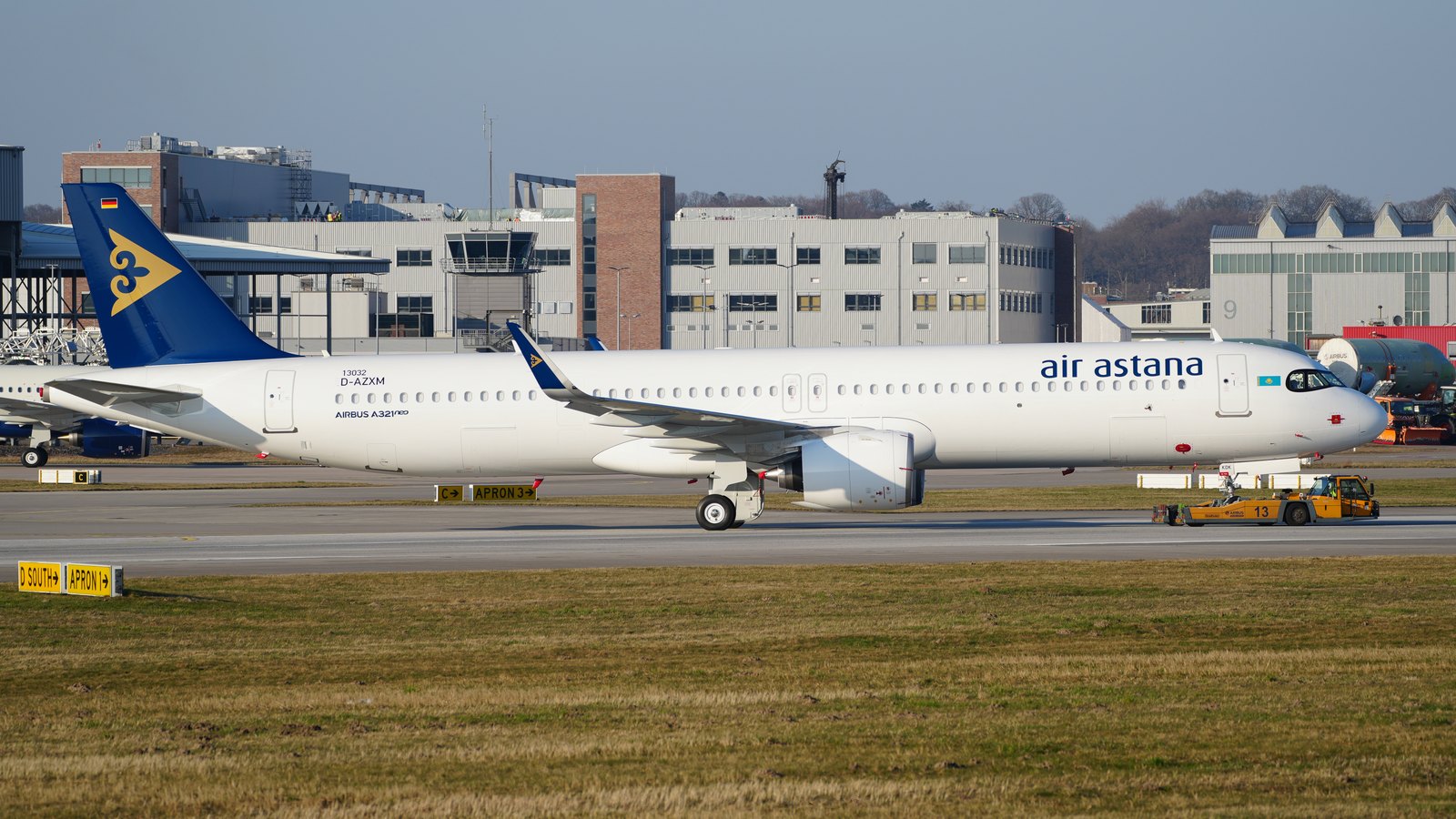 A white Air Astana airliner being towed across an airfield