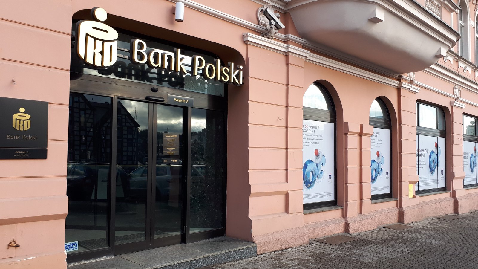 The entrance of a PKO Bank Polski branch in a pink historic building, with the bank's logo above the door